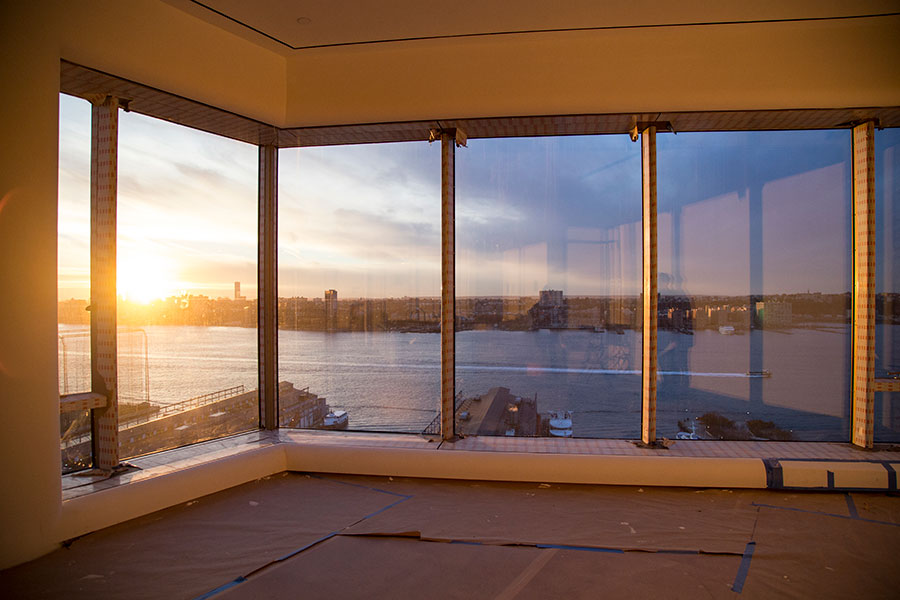 Panoramica di una stanza vuota, con 5 grandi finestre a tutto vetro e affaccio su un fiume al tramonto